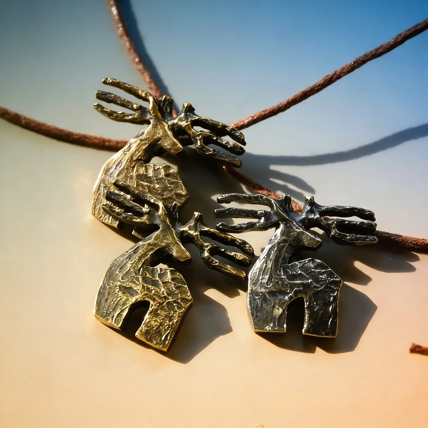 Three handmade Georgian deer necklaces in brass, silver, and cord materials
